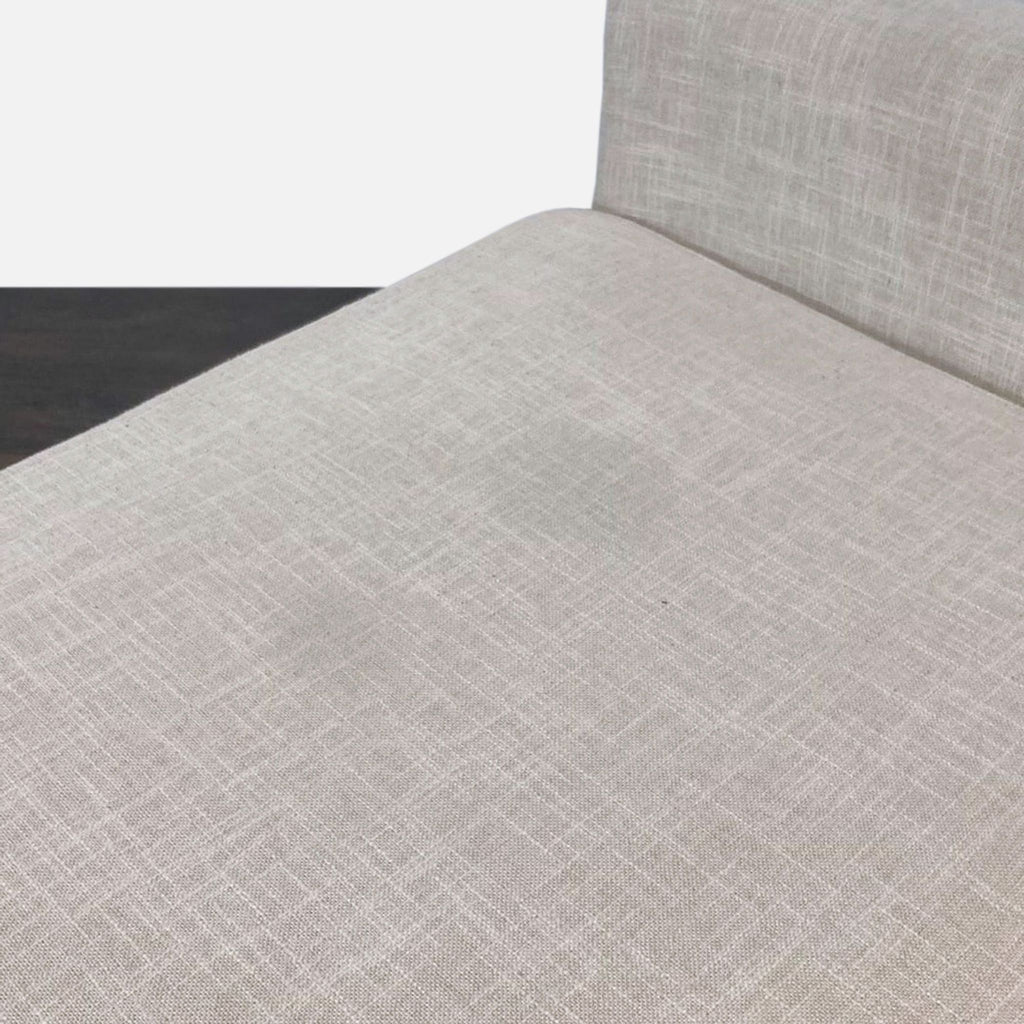 2. Close-up of a light beige loveseat's textured upholstery showing the seat and part of the backrest.