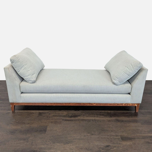 Modern light gray chaise sofa with wooden base and pillows, perfect for relaxing in any room.