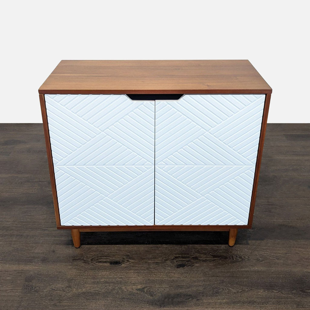 West Elm wood cabinet with white geometric doors and two roomy interior shelves for storage.