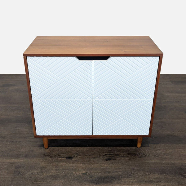 West Elm wood cabinet with white geometric doors and two roomy interior shelves for storage.