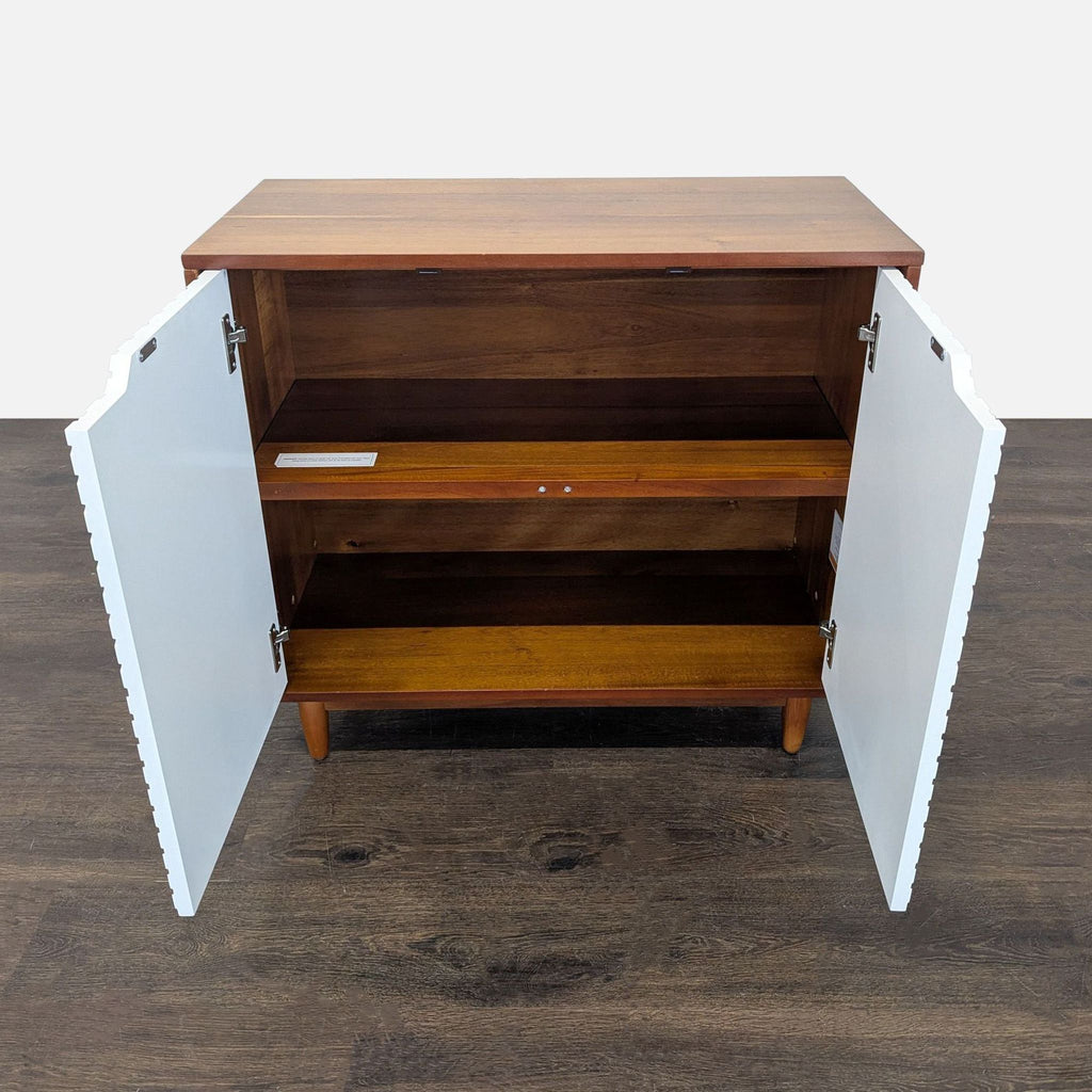 Modern West Elm cabinet featuring white patterned doors and two spacious inside shelves for organization.