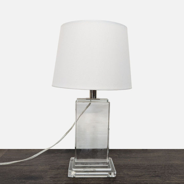 Modern table lamp with clear base and white shade, suitable for desks or nightstands.