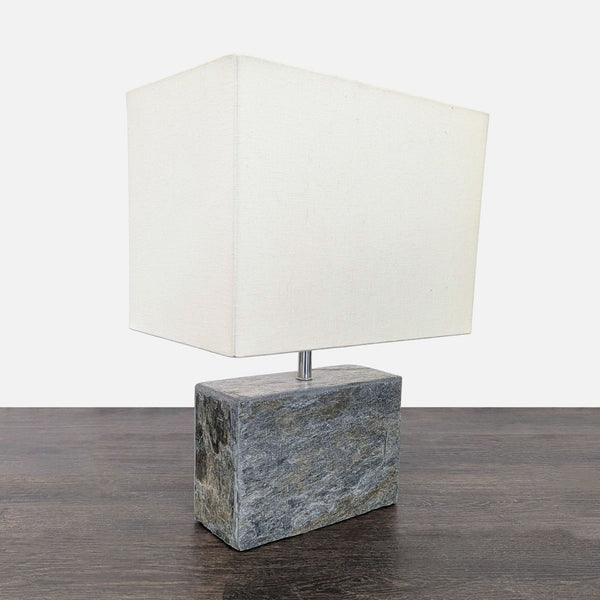 Modern table lamp with a solid stone base and a white rectangular shade, ideal for contemporary spaces.  