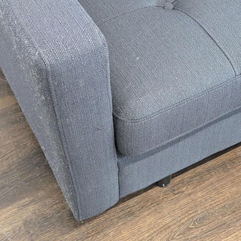 Modern dark gray loveseat with simple lines, tufted cushions, and wood legs, ideal for apartments or offices.