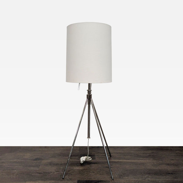 Modern floor lamp with chrome tripod base, white shade, and dual pull chains, suitable for various rooms.