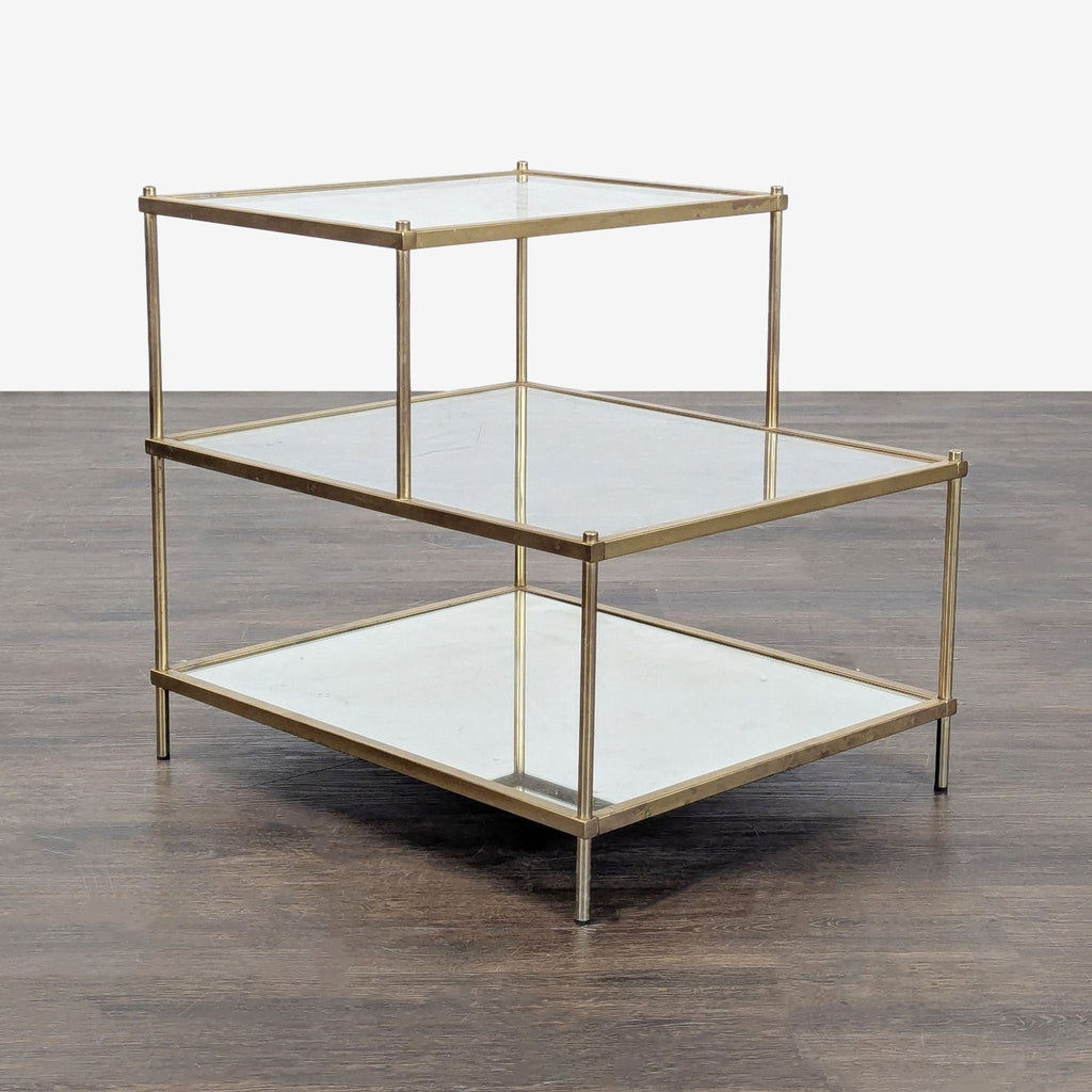 Modern end table with a gold metal frame, two clear glass shelves, and a mirrored bottom shelf.