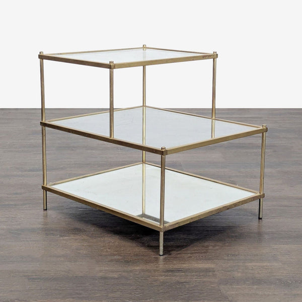 Modern end table with a gold metal frame, two clear glass shelves, and a mirrored bottom shelf.