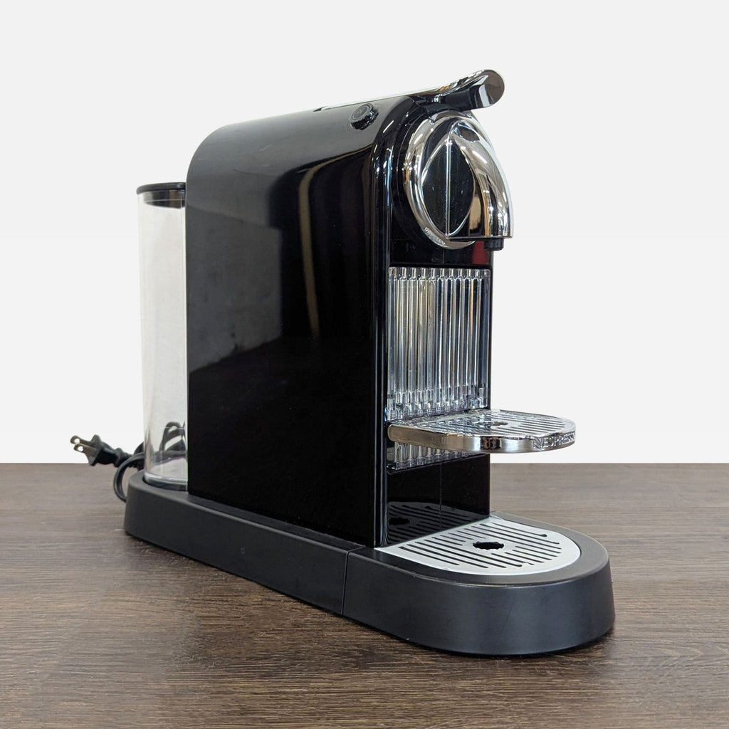 Compact Nespresso coffee maker in black, fits small spaces, includes removable water tank and drip tray.  