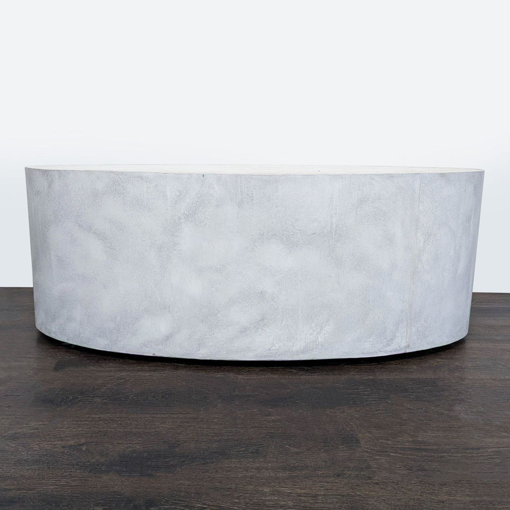 Modern oval coffee table mimicking solid stone, featuring a sleek polished surface and recessed wheels.