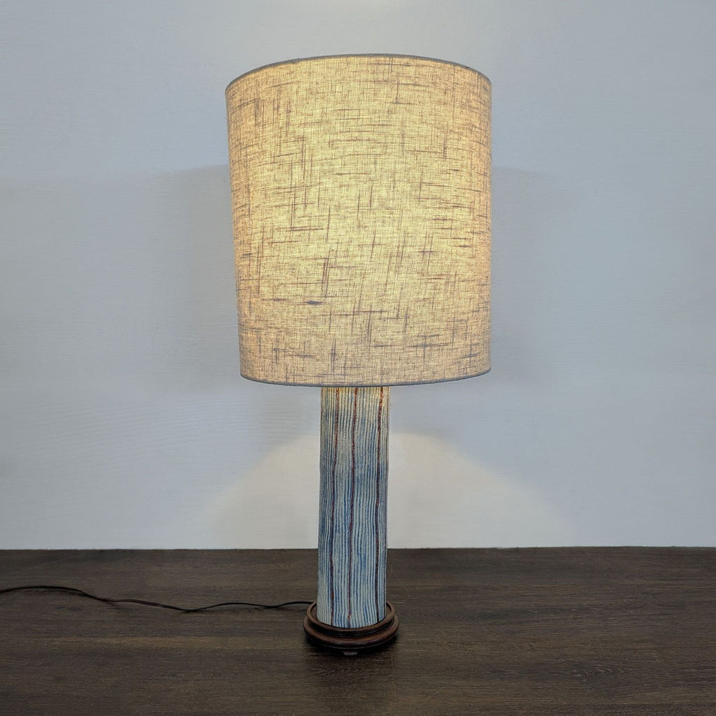 Table lamp with textured pottery base in blue and brown stripes and soft beige shade, suitable for any room.