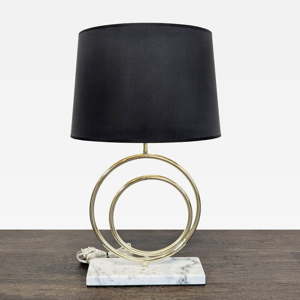 Modern table lamp with a black shade, gold circular accents, and a marble base, ideal for any room.