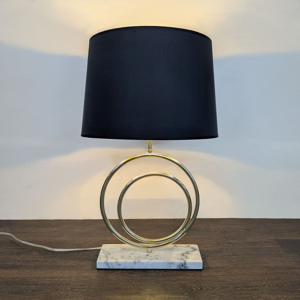 Chic lighting: black-shaded lamp with stylish gold rings and marble base, perfect for living or office spaces.