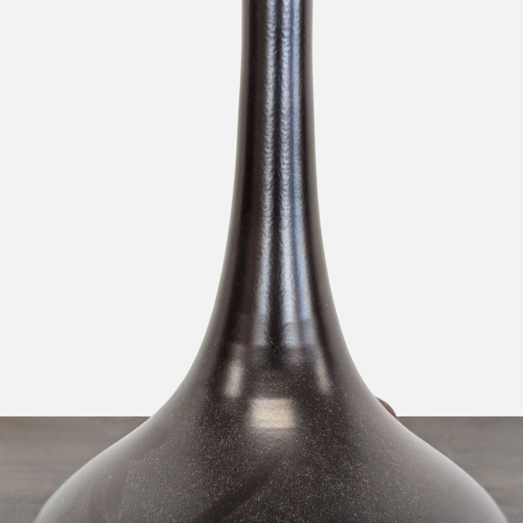 Close-up detail of the lamp’s glossy, curved black base, highlighting its modern, sturdy construction for lighting.
