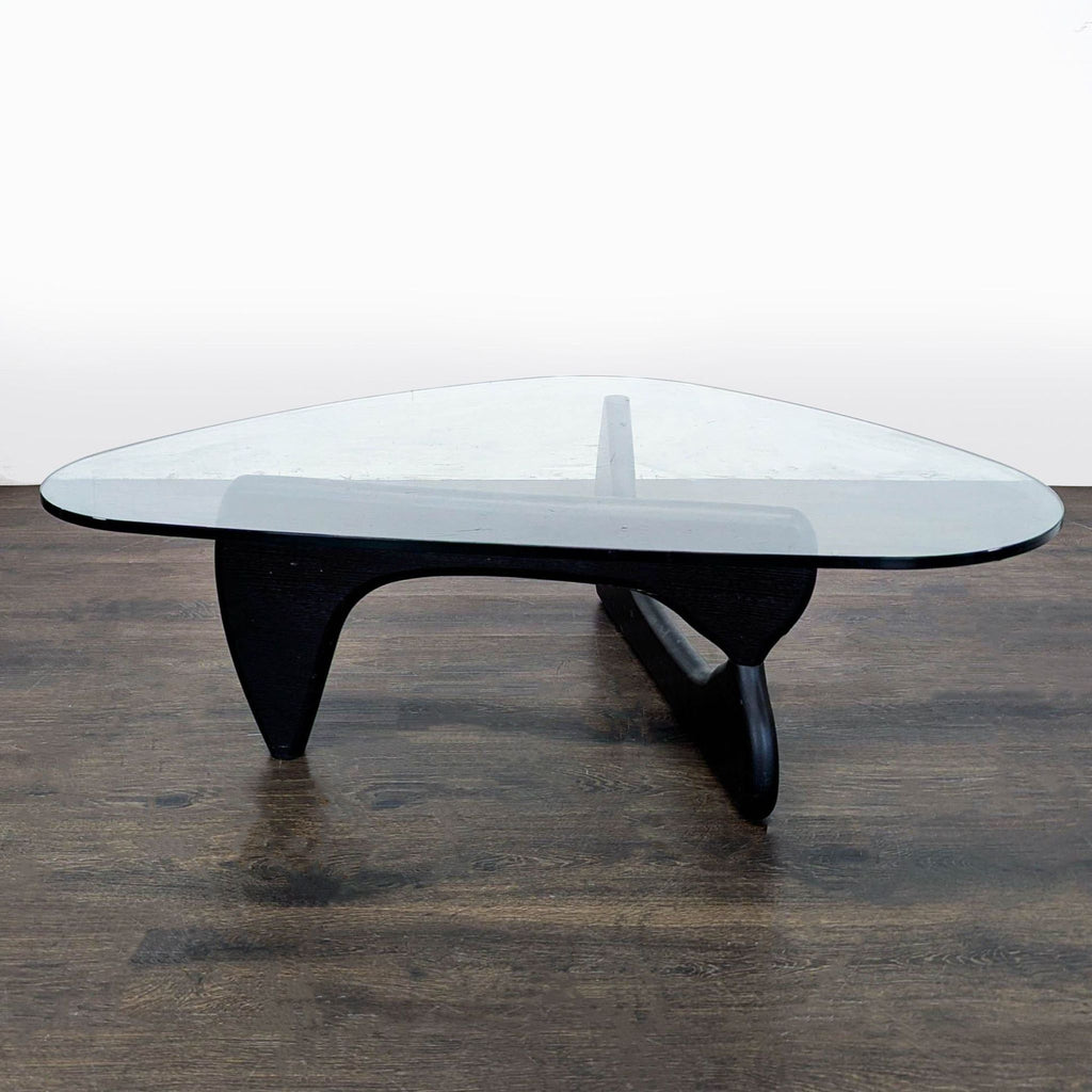 Noguchi coffee table featuring two curved wood pieces supporting a thick, oval-shaped glass tabletop.