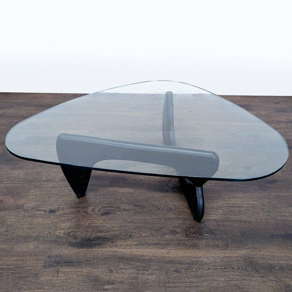 Mid-century coffee table with distinctive sculpted wood base and seamless glass top, designed by Isamu Noguchi.
