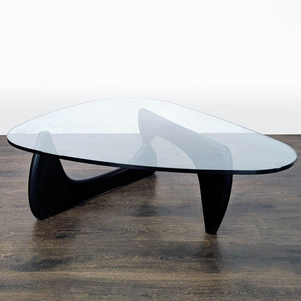 Modernist Noguchi coffee table with sculptural wooden base and clear glass top, designed by Isamu Noguchi.