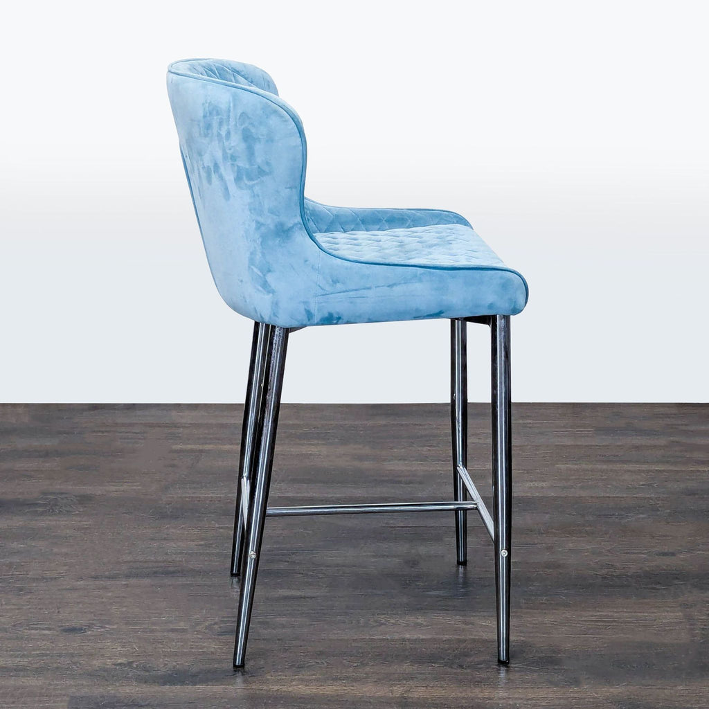 Modern blue velvet stool with elegant quilted back and seat, supported by sturdy chrome legs.