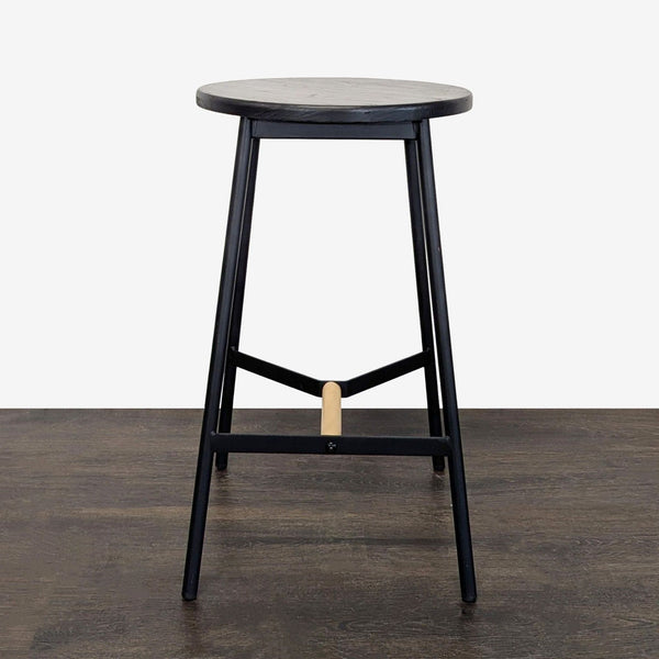 Black round metal stool with wooden seat and natural wood footrest, ideal for modern kitchens or bars.