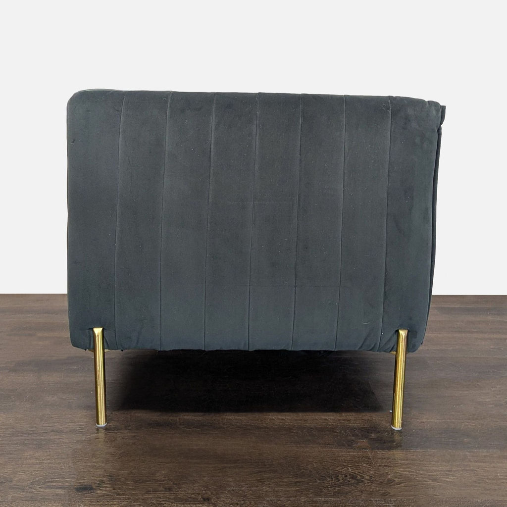 Boxy lounge chair in deep grey velvet with gold legs, offering comfy cushioning and vertical side stitching.