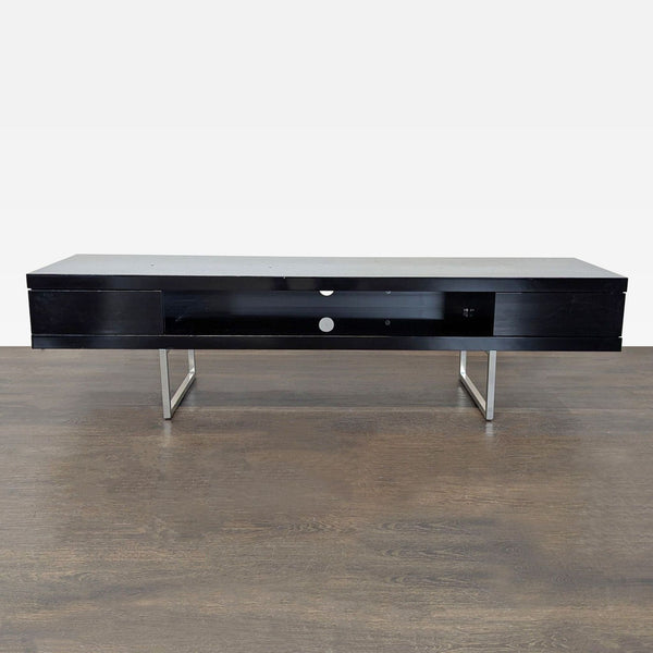 Sleek black entertainment center with metal legs, open shelf for electronics, two drawers, and cable holes.