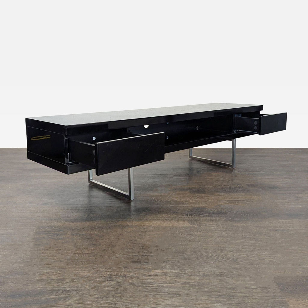 Modern black media console with sled legs, open electronics shelf, two large drawers, and organized cord access.
