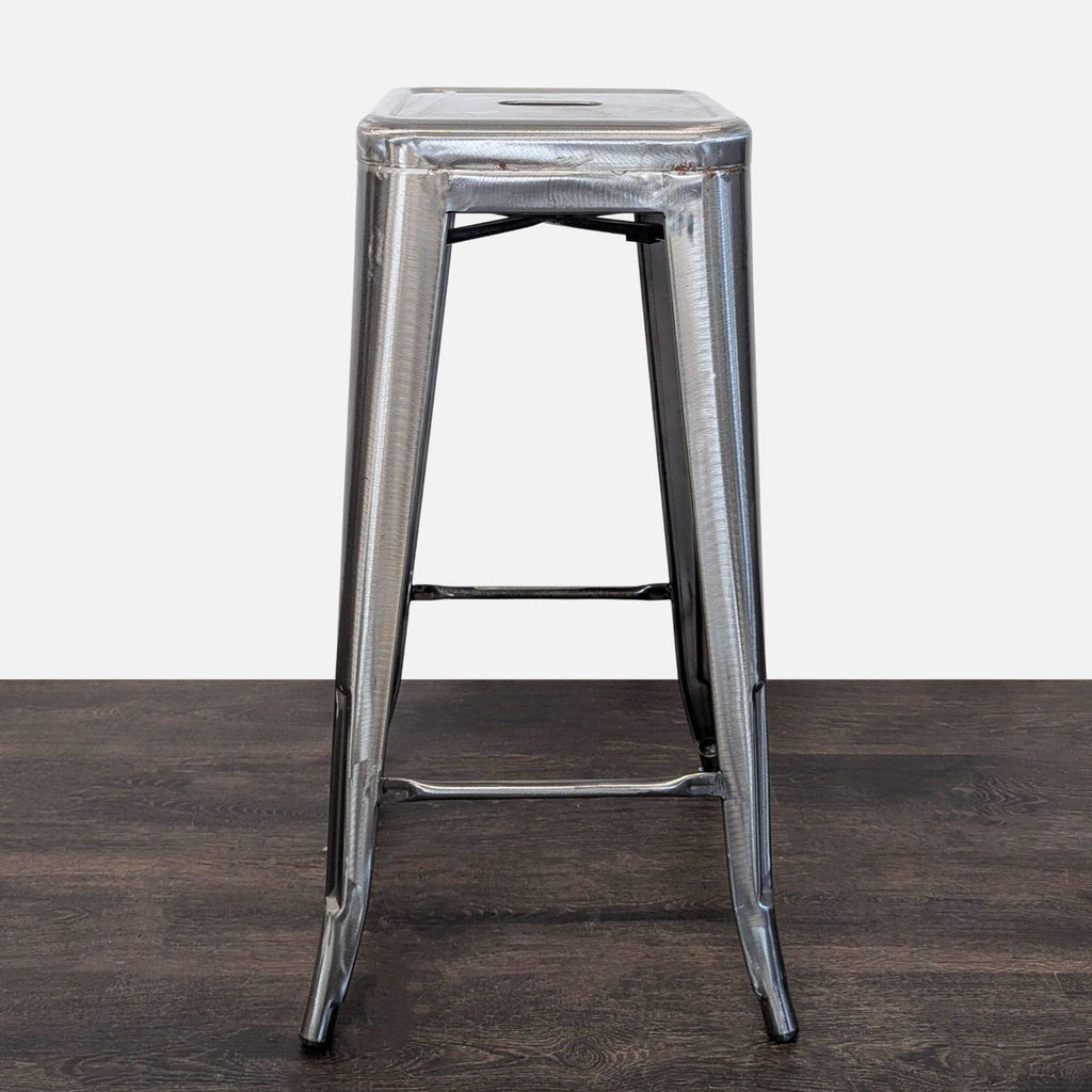 Brushed steel bar stool with footrest, showcasing a modern industrial design for kitchens or bars.
