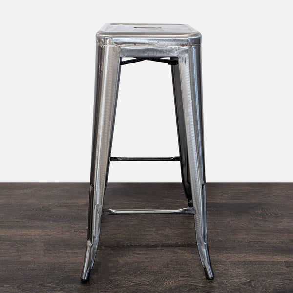 Brushed steel bar stool with footrest, showcasing a modern industrial design for kitchens or bars.