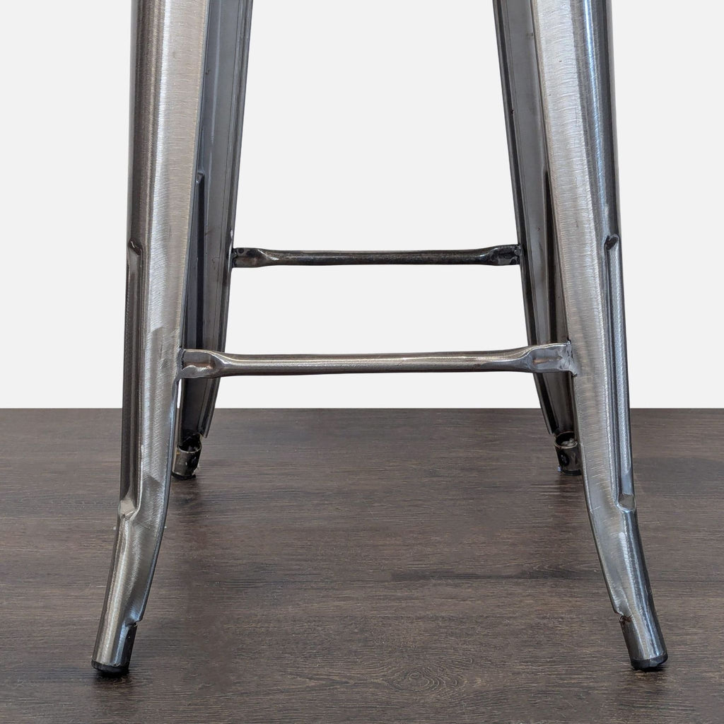 Modern industrial stool in brushed steel, featuring a footrest and portable build for versatile seating.