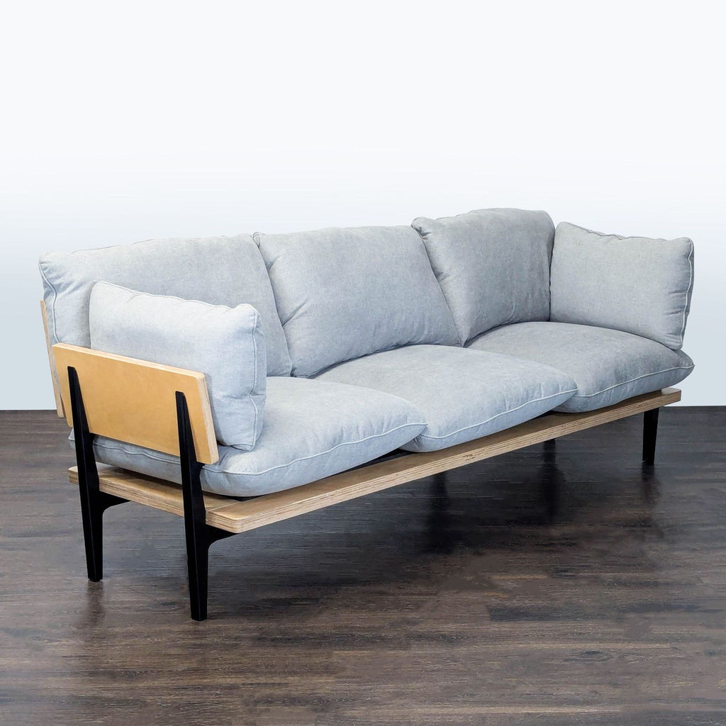 Modern Floyd Home 3-seater featuring cozy gray upholstery, sleek lines, and a wood-metal frame.