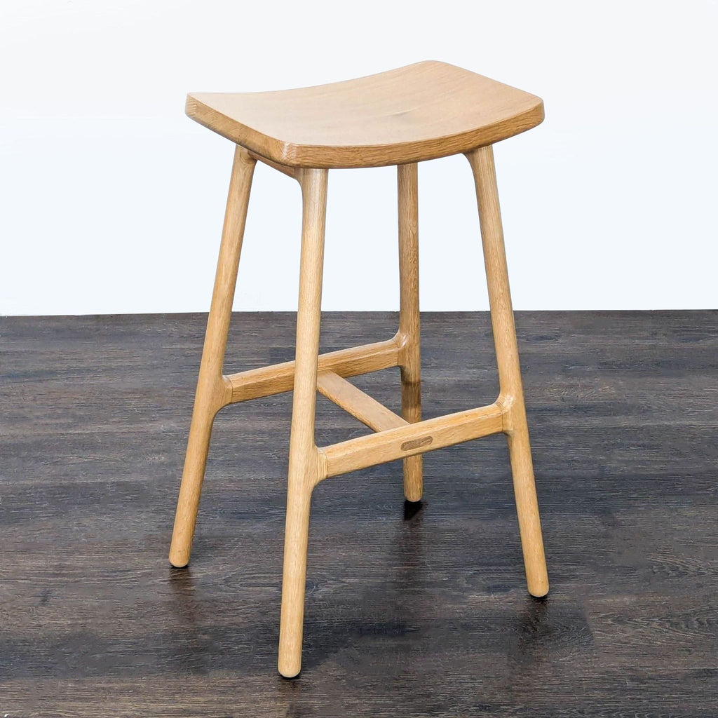Natural wood Article stool with a sleek, curved seat and compact build, perfect for counters or as extra seating.