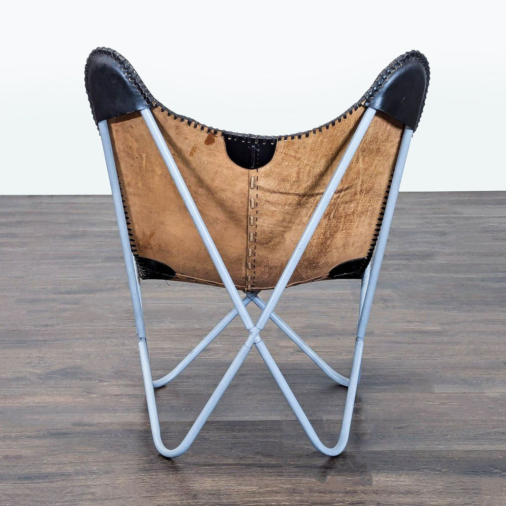 Modern butterfly lounge chair featuring a dual-tone leather seat and a sturdy blue frame for stylish comfort.  