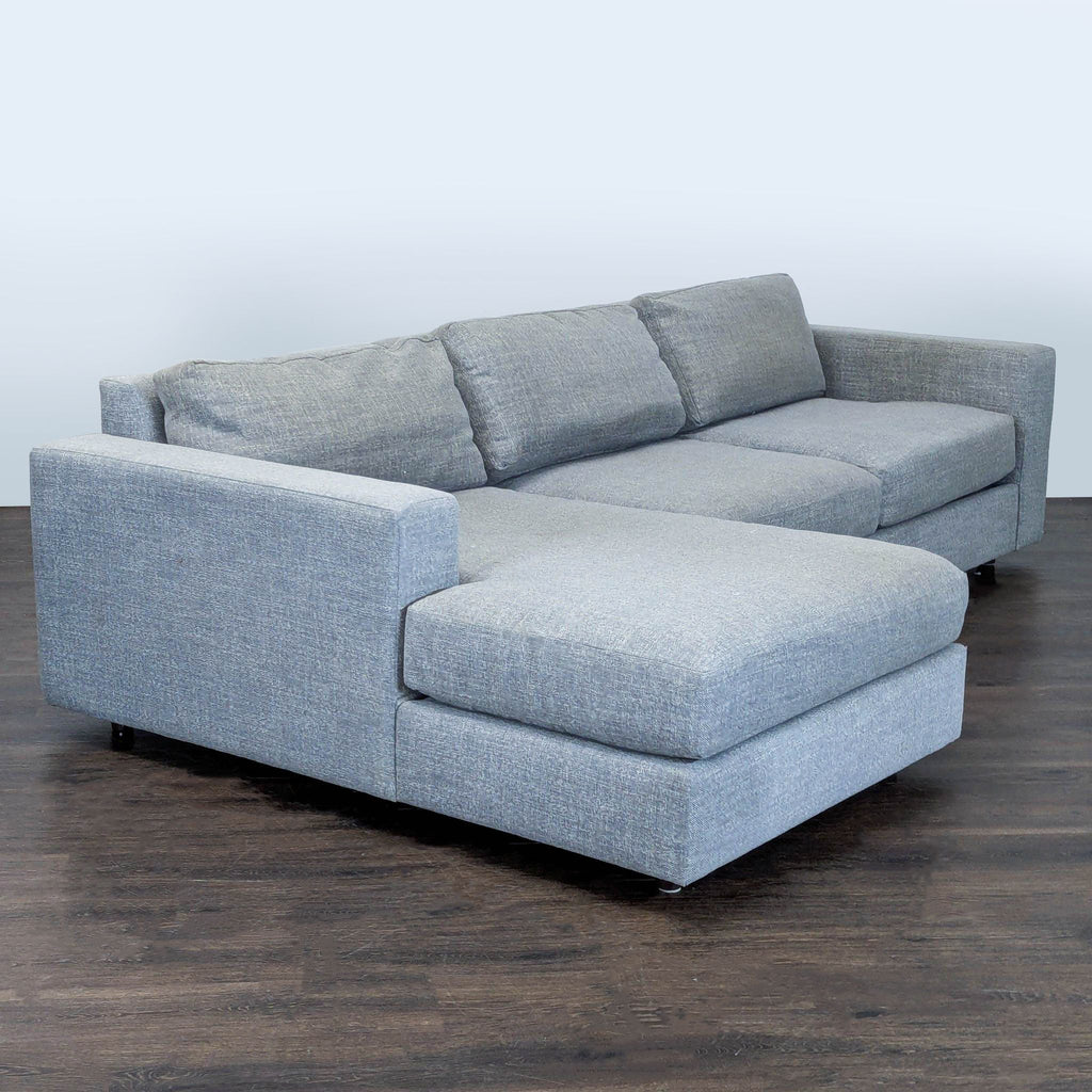 Modern gray West Elm sectional sofa featuring spacious chaise and plush cushions, ideal for relaxing or gatherings.  