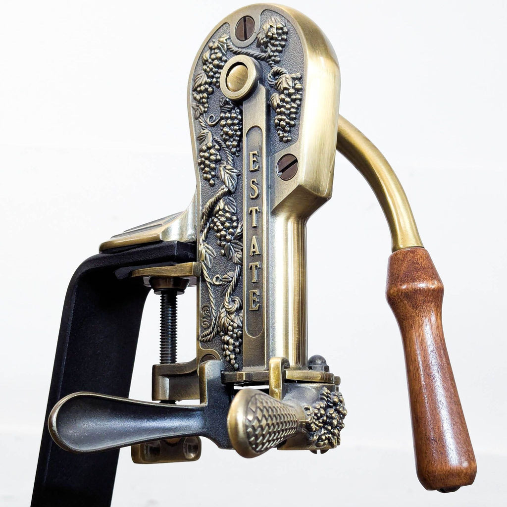 Ornate mechanical wine bottle opener by Rogar Estate, featuring brass accents, wood crank, and black display base.  