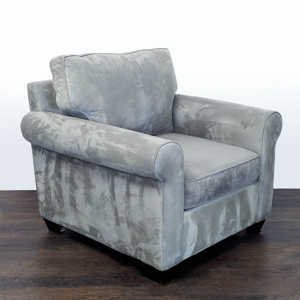 2. Angled side view of a gray Pottery Barn lounge chair showing its soft upholstery and rounded armrests.  