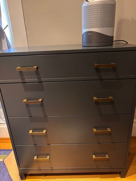 1. Modern dark gray dresser by The Land of Nod with four drawers and brass handles, air purifier on top.  