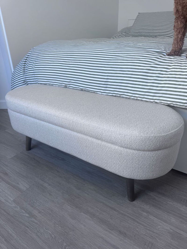 1. Light beige upholstered bench with rounded edges from Walmart Sofa, placed at the foot of a bed with striped bedding.