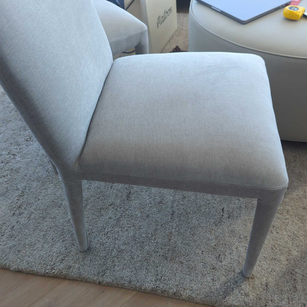 Light grey upholstered dining chair by Moe's Home Collection, shown angled over a carpeted floor.