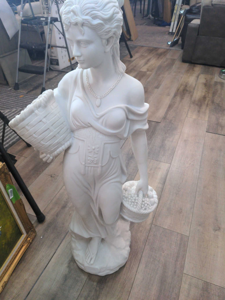 a large white marble statue of a woman holding a basket and a basket.