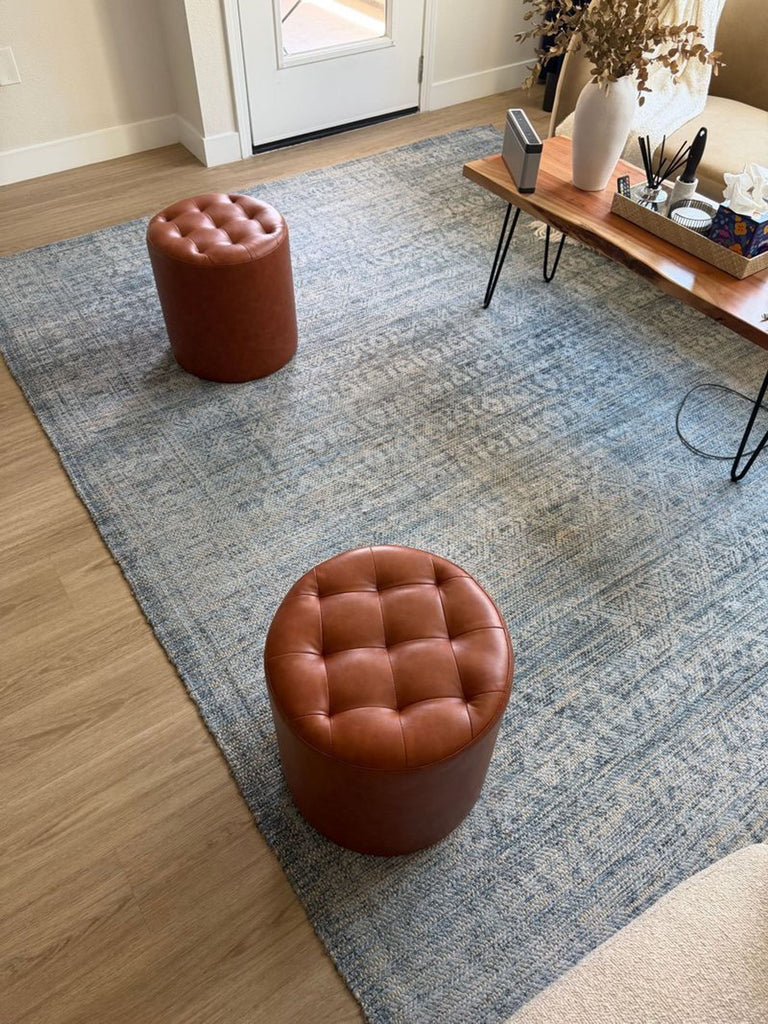 1. Light blue patterned West Elm rug in a living room with tan stools and a wooden coffee table.