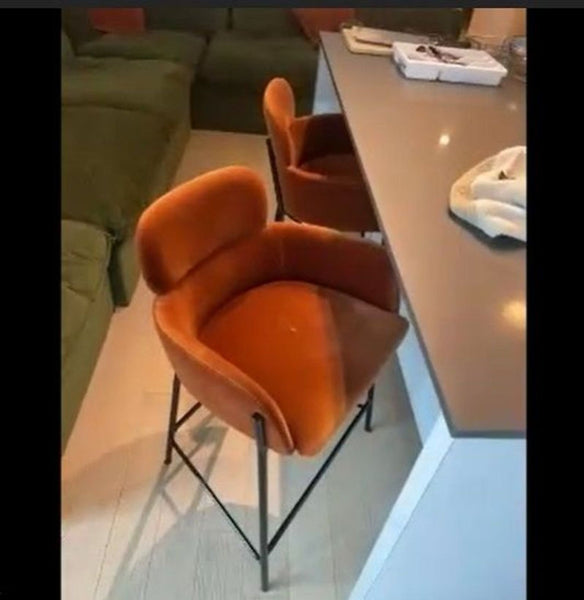 1. Orange velvet counter stool with black metal legs from 4x chairs, shown at a modern kitchen counter.