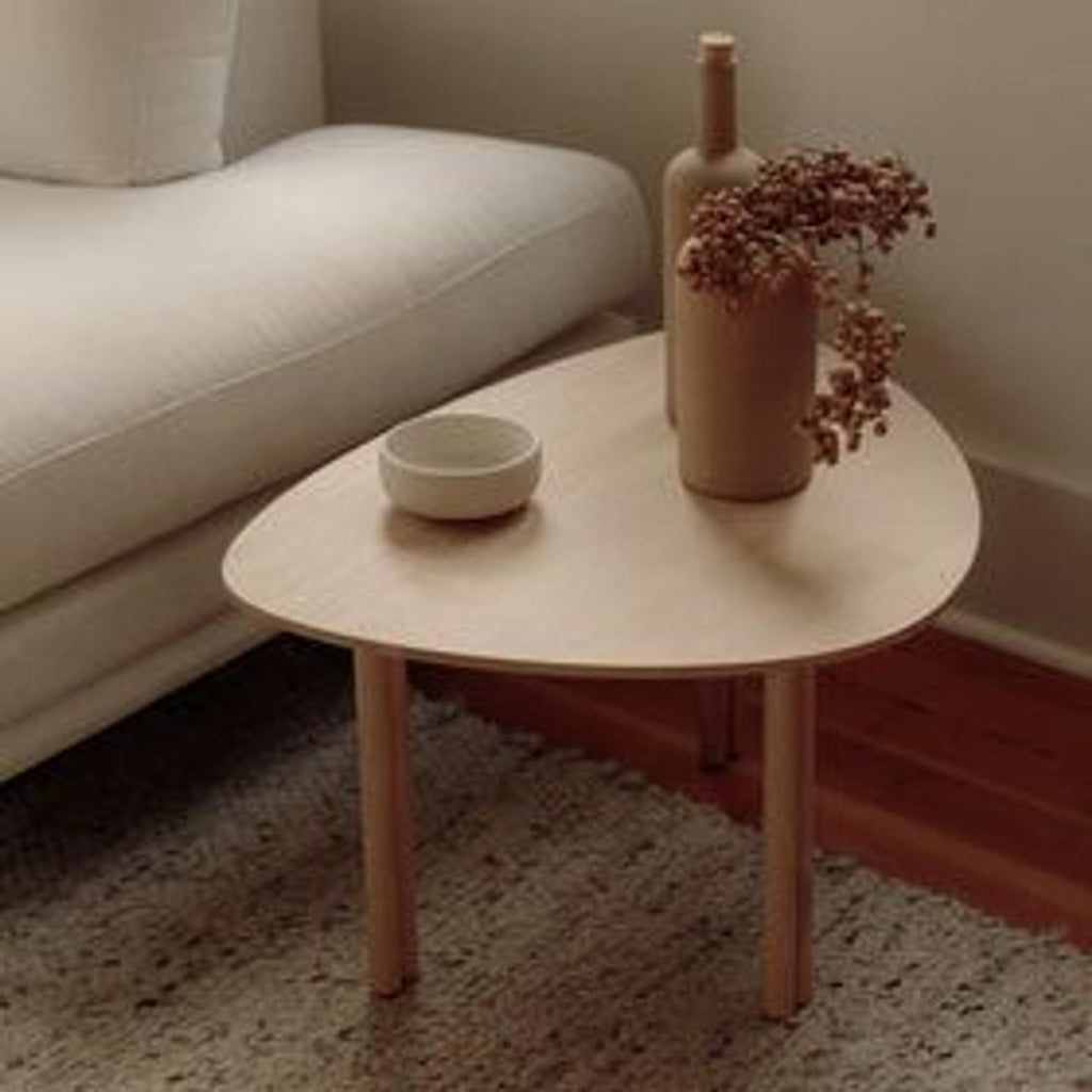 2. White ash coffee table by Sundays placed by a sofa, decorated with a bowl and vase in a cozy room.
