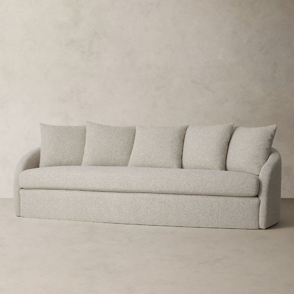 a grey sofa with three pillows on it.