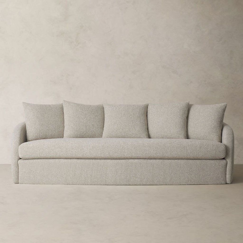 a grey sofa with three pillows on it.