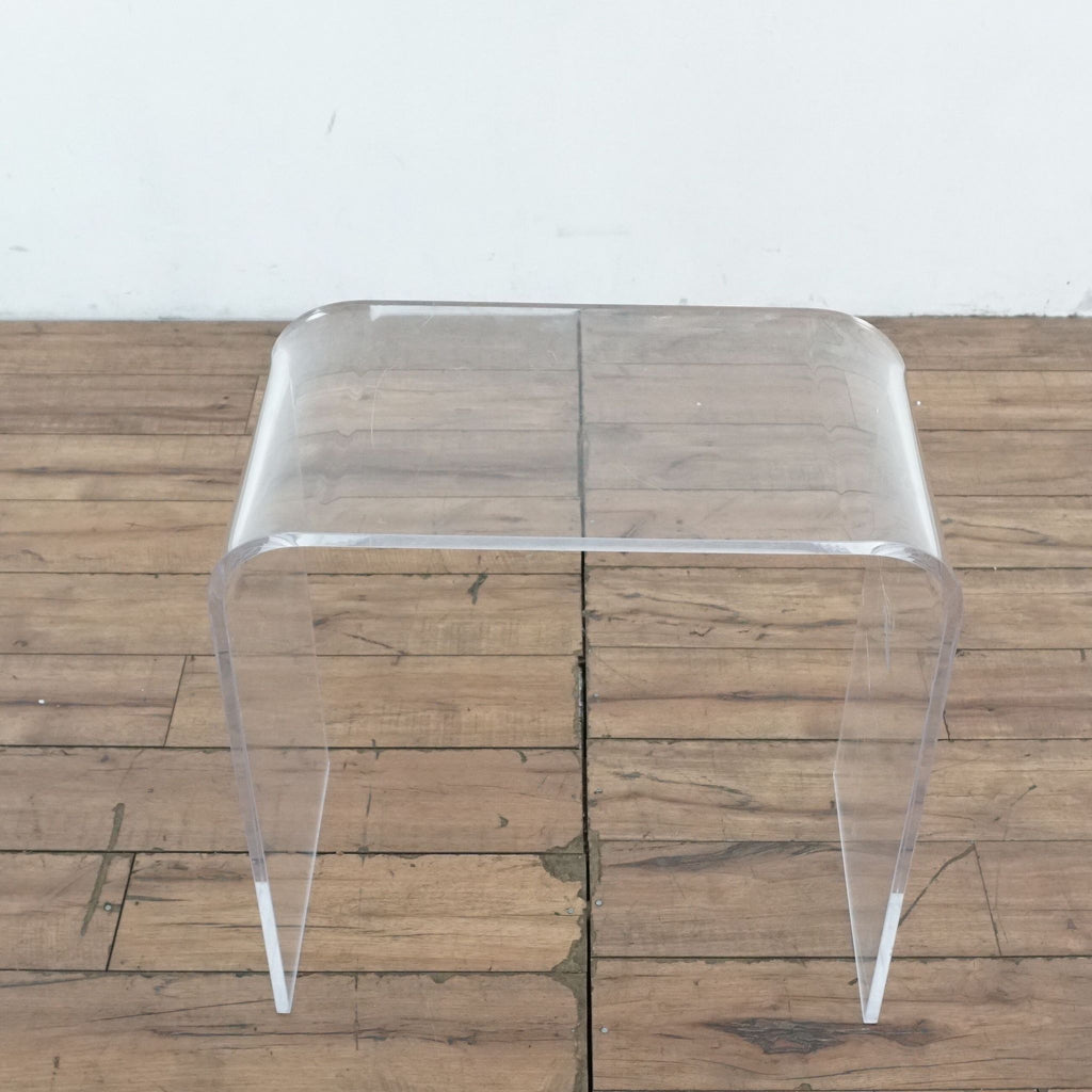 1. Transparent Reperch end table with waterfall style design, shown on a wooden floor against a white wall.