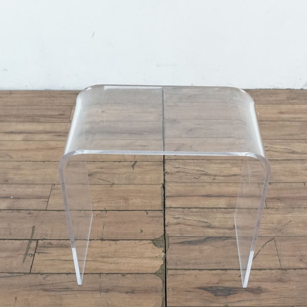 1. Transparent Reperch end table with waterfall style design, shown on a wooden floor against a white wall.