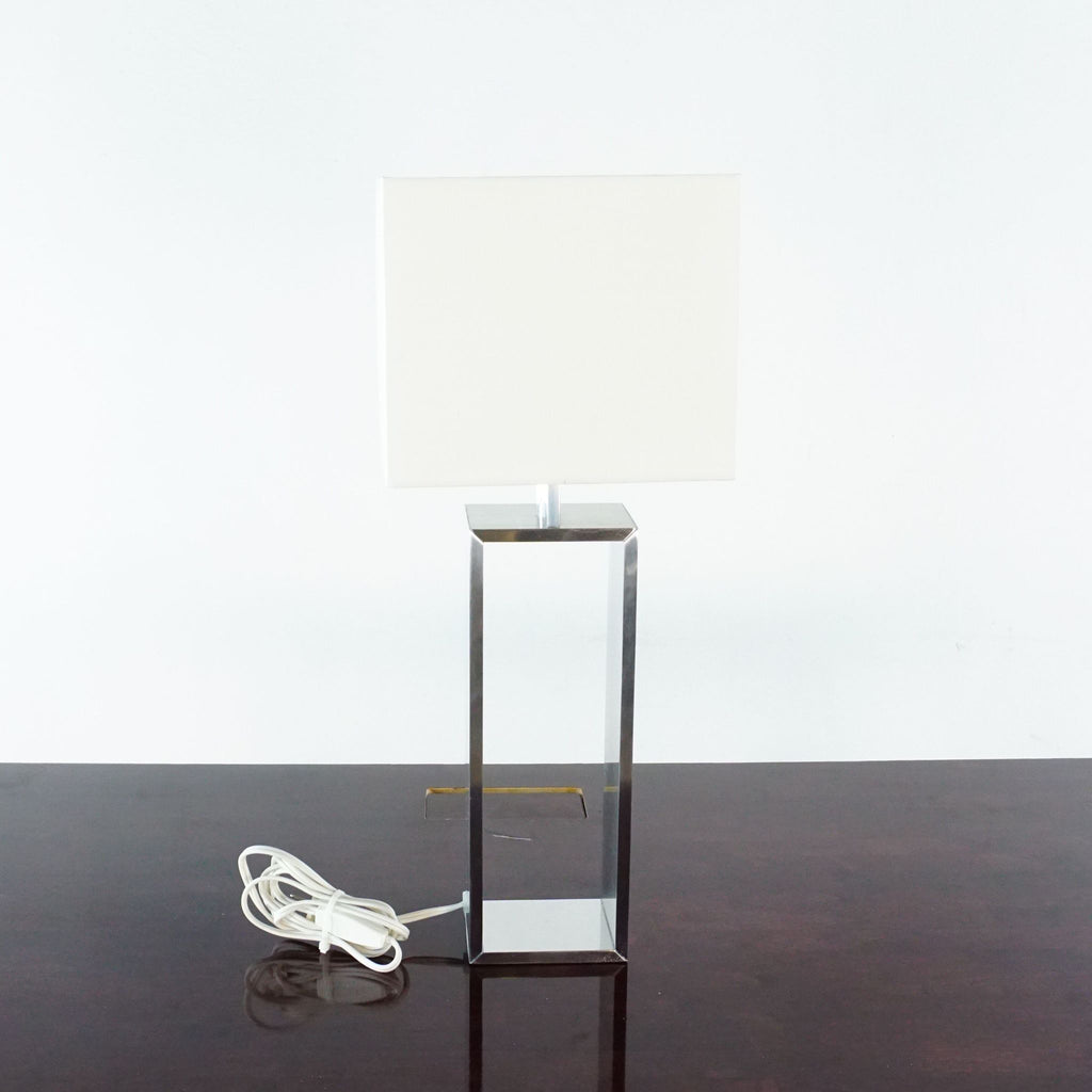 1. Ikea table lamp with an aluminum rectangular base and white square shade, placed on a dark surface.