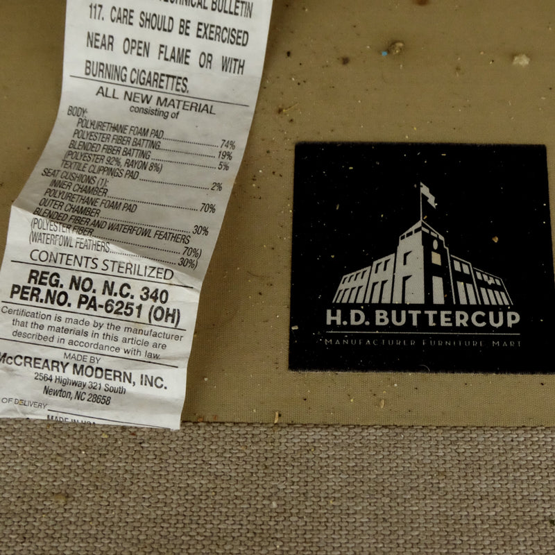 Closeup of an H.D. Buttercup label and materials tag attached to the underside of the sofa.  