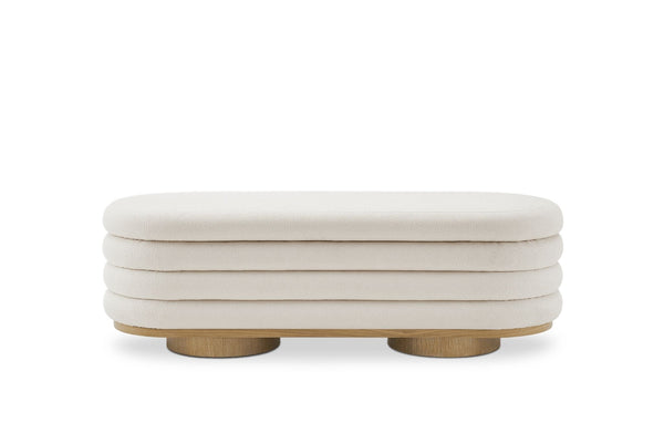 1. Front view of a Reperch ottoman bench with tiered cream upholstery and round wooden legs. 
