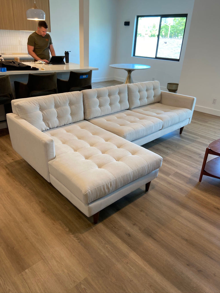 CB2 cream-colored sectional with modern tufted upholstery, wood legs, and a deep lounge seat in great condition.  