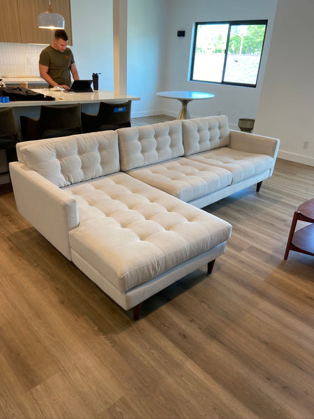 CB2 cream-colored sectional with modern tufted upholstery, wood legs, and a deep lounge seat in great condition.  